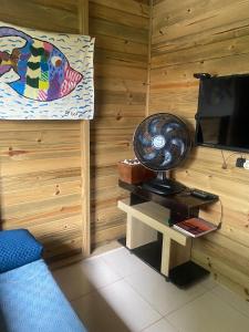 a room with a bed and a table with a television at Paraíso do Rosa in Praia do Rosa