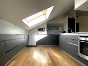 a kitchen with a skylight in the ceiling with a sink and a stove at Ático en Plaza de la Constitución 3 bedrooms in Málaga +80 photos