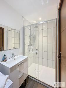 een witte badkamer met douche en wastafel bij La Marée - Appt à 50m de la plage in Bray-Dunes