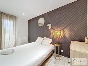 een slaapkamer met een groot wit bed en een muur bij La Marée - Appt à 50m de la plage in Bray-Dunes