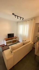 Una sala de estar con un sofá blanco y un televisor. en Apartamento aconchegante no Setor Bueno, en Goiânia