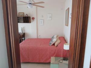 a bedroom with a red bed and a ceiling fan at La Traiña in Adra