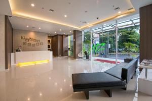 a lobby with a black couch and a table at Whiz Prime Hotel Hasanuddin Makassar in Makassar