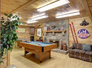 Una mesa de billar en una habitación con chimenea de piedra. en Game room, hot tub, flat easy drive to 3BR cabin!, en Sevierville