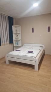 a white bed in a room with a wooden floor at Central Apartment in Vitez