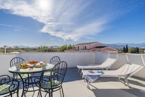 a patio with two tables and chairs on a balcony at Lighthouse Holiday Home in Àrbatax