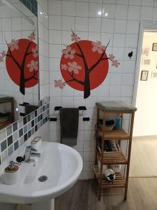 łazienka z umywalką i czerwonymi kwiatami na ścianie w obiekcie Apartamento Shenzhen en Astorga Camino de Santiago Cochera bicis w mieście Astorga