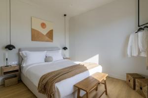 a bedroom with a white bed and a wooden bench at Acropolis Penthouse Plunge Pool in Athens