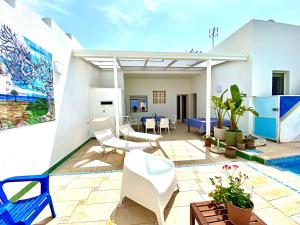 Un patio con sillas blancas y una piscina. en Casa Mondrian - Comfort e Design con Piscina Privata, en Tiggiano