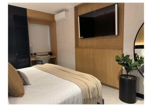 a bedroom with a bed and a flat screen tv at Hotel Aló Degollado in Guadalajara