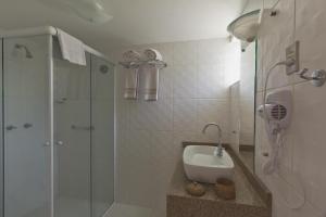 a white bathroom with a shower and a sink at Resort Fazenda 3 Pinheiros in Engenheiro Passos