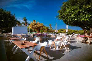 a group of tables and white chairs and tables and trees at Malama Beach Holiday Village in Protaras