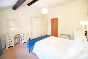 ein weißes Schlafzimmer mit einem Bett und einem Spiegel in der Unterkunft Hafan Cottage in Caernarfon