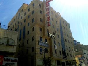 Un palazzo alto con un cartello sul lato. di Queen Plaza Hotel a Hebron