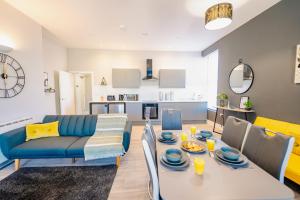 a living room with a table and a blue couch at LUXURY SPACIOUS 2-BED & High Ceiling in Cardiff +12 photos