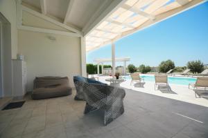 a patio with a couch and chairs and a pool at Villa Aria - Modica in Modica