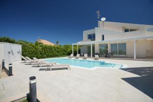 a villa with a swimming pool in front of a house at Villa Aria - Modica in Modica
