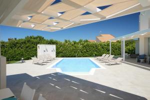 a swimming pool in a patio with lounge chairs and a swimming poolvisor at Villa Aria - Modica in Modica