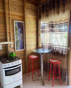 a kitchen with a stove and two red stools at Paraíso do Rosa in Praia do Rosa