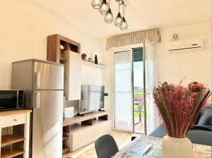 een keuken met een koelkast en een tafel met een vaas met bloemen bij Appartamento Spiga in San Vincenzo