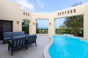 a swimming pool in a house with chairs and a patio at Luxury villa with private pool in Ras al Khaimah