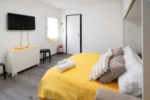 a bedroom with a yellow bed with pillows and a television at Girasole in Chioggia