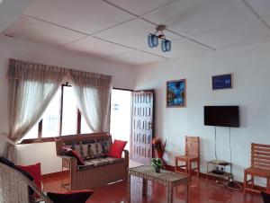a living room with a couch and a tv at Landa's Guest House in Praia do Tofo