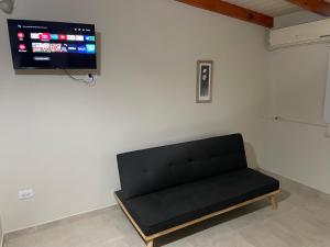 Sofá negro en una habitación con TV de pantalla plana en Cacho's house, en Junín