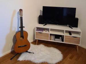 a guitar sitting in a living room next to a tv at 1Step2AllCities House&Garden in Wuppertal