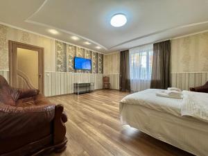 a bedroom with a bed and a chair and a television at ApartPoltava 100 квадратних метрів затишку в серці Полтави, Корпусний парк, Банківський ЧЕК in Poltava +20 photos