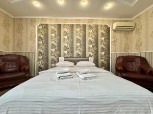 a bedroom with two chairs and a large bed at ApartPoltava 100 квадратних метрів затишку в серці Полтави, Корпусний парк, Банківський ЧЕК in Poltava