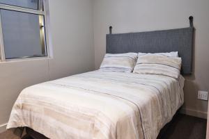 1 dormitorio con 1 cama con manta blanca y ventana en 126 Andringa Walk, en Stellenbosch
