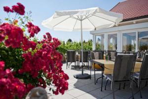 une terrasse avec des tables, un parasol blanc et des fleurs dans l'établissement Felshof - Weingut & Gästehaus, à Sommerhausen