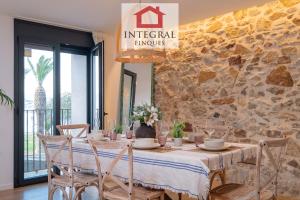 a dining room with a table and a stone wall at Apartament Bella Terra in Palamós