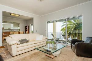 a living room with a white couch and a glass table at Palmeira`s Village in São Gonçalo