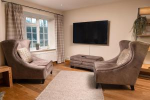 a living room with two chairs and a flat screen tv at Riverside Walk in Airton