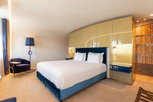 a bedroom with a large white bed and a chair at CBR Boutique Hotel - Coimbra in Coimbra