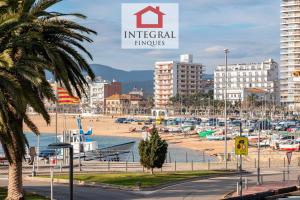 a beach with boats in the water and buildings at Apartament Bella Terra in Palamós