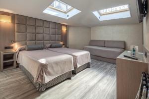 a bedroom with a bed and a couch and skylights at Hotel Suizo in Barcelona