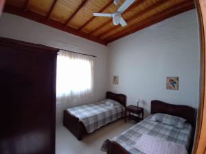 ein Schlafzimmer mit zwei Betten und einem Deckenventilator in der Unterkunft Casa ecológica, cheia de conforto, em reserva agroecológica in Espirito Santo Do Pinhal