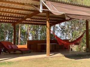 eine Hängematte unter einer Pergola mit einer Bank und Bäumen in der Unterkunft Casa ecológica, cheia de conforto, em reserva agroecológica in Espirito Santo Do Pinhal