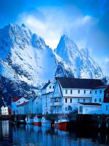 a group of houses and boats in the water with a mountain at Modern One-Bedroom Apartment in Henningsvær