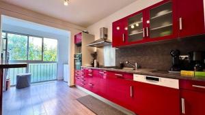 a kitchen with red cabinets and a large window at Casamea - Spacieux T3 famille, Vue mer, Parking in Ajaccio