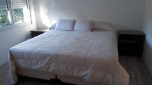 a bedroom with a bed with white sheets and a window at Casa en Miramar Alquiler temporario in Miramar