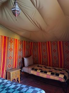 1 dormitorio en una tienda de campaña con 1 cama y 1 mesa en Nomada Desert Camp, en Merzouga 129 fotos más