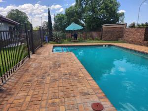 a swimming pool with a brick fence and an umbrella at Gift from G guesthouse in eMalahleni