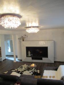 a living room with a fireplace and chandeliers at Schneider House in Ramstein-Miesenbach