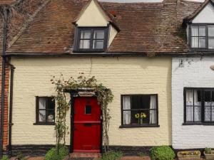 a red door on a white house with windows at Runnymede in Tewkesbury