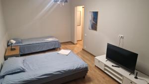 a room with two beds and a flat screen tv at Apartamentai Naujojoje Akmenėje in Naujoji Akmenė