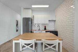 a kitchen with a wooden table and two white stools at Bonito Apartamento Delfin Amarillo by Paramount Holidays in Santiago del Teide